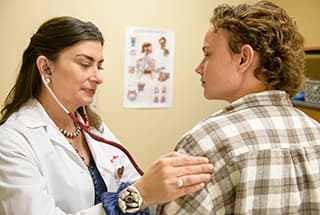 doctor uses stethoscope on patient