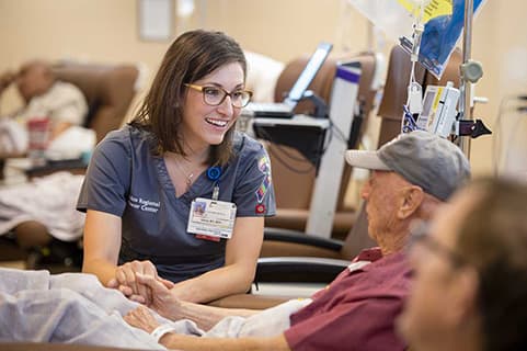Presbyterian nurse navigator talks with cancer patient receiving chemotherapy.