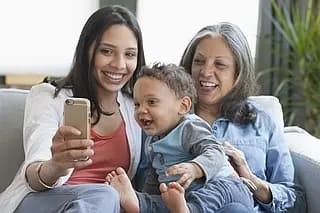 Three generations of a family sit on a couch.