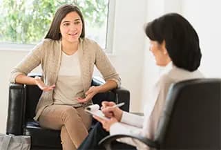 Patient talks with doctors, both are sitting in chairs.