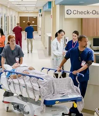 Nurses roll patient through hospital hallways.