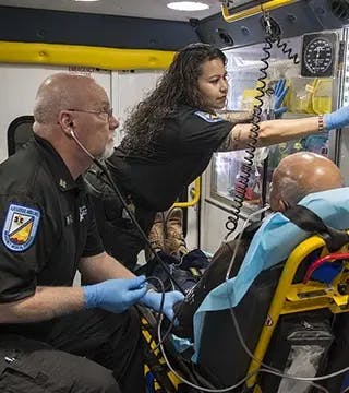 Paramedics help a patient inside an ambulance.