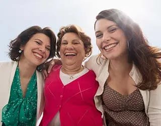 Three women smiling with their arms around each other