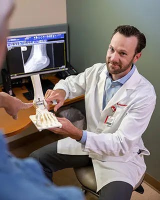 Doctor displays bone model for patient