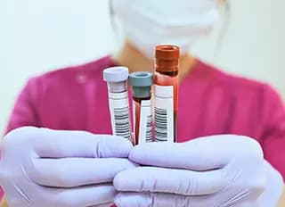 Nurse holds up three vials of blood.