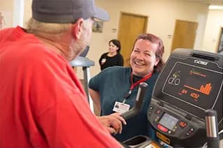 Man on workout equipment talks with medical team