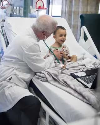 Doctor holds stethoscope to smiling child's chest