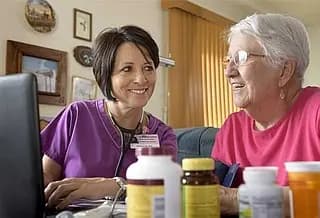 Woman and healthcare professional sit at table in her home.