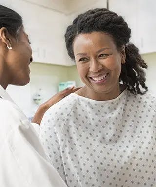 Doctor comforts smiling woman in medical gown
