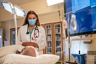 Doctor talks with patient on hospital bed