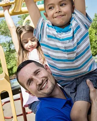 Dad helps kids on the playground.