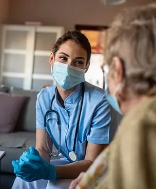 Nurse in mask and gloves looks at patient.