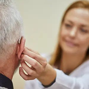 Doctor adjusts patient hearing aid